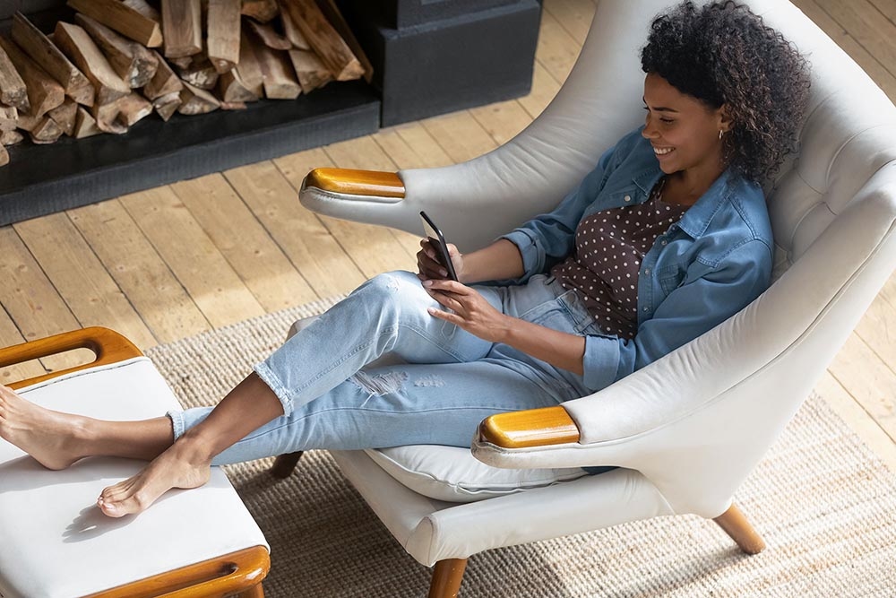 A relaxed individual using a mobile phone in a cozy chair.