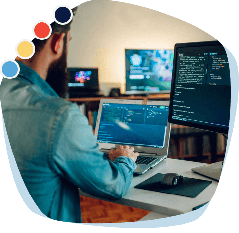 A person coding on a laptop with multiple screens, highlighted with colorful icons in the corner.