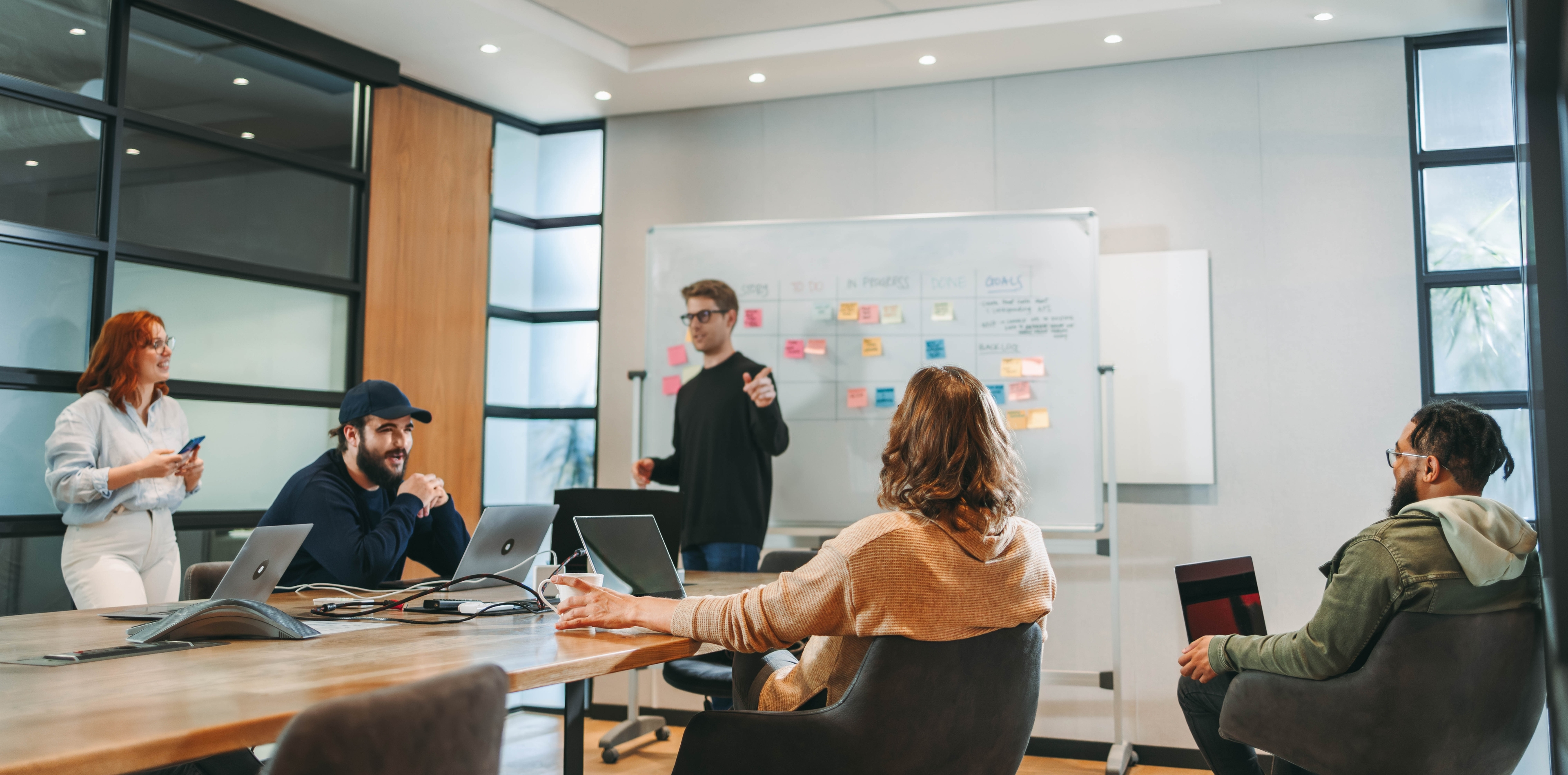 Team members discussing tasks and progress with a whiteboard in the background.