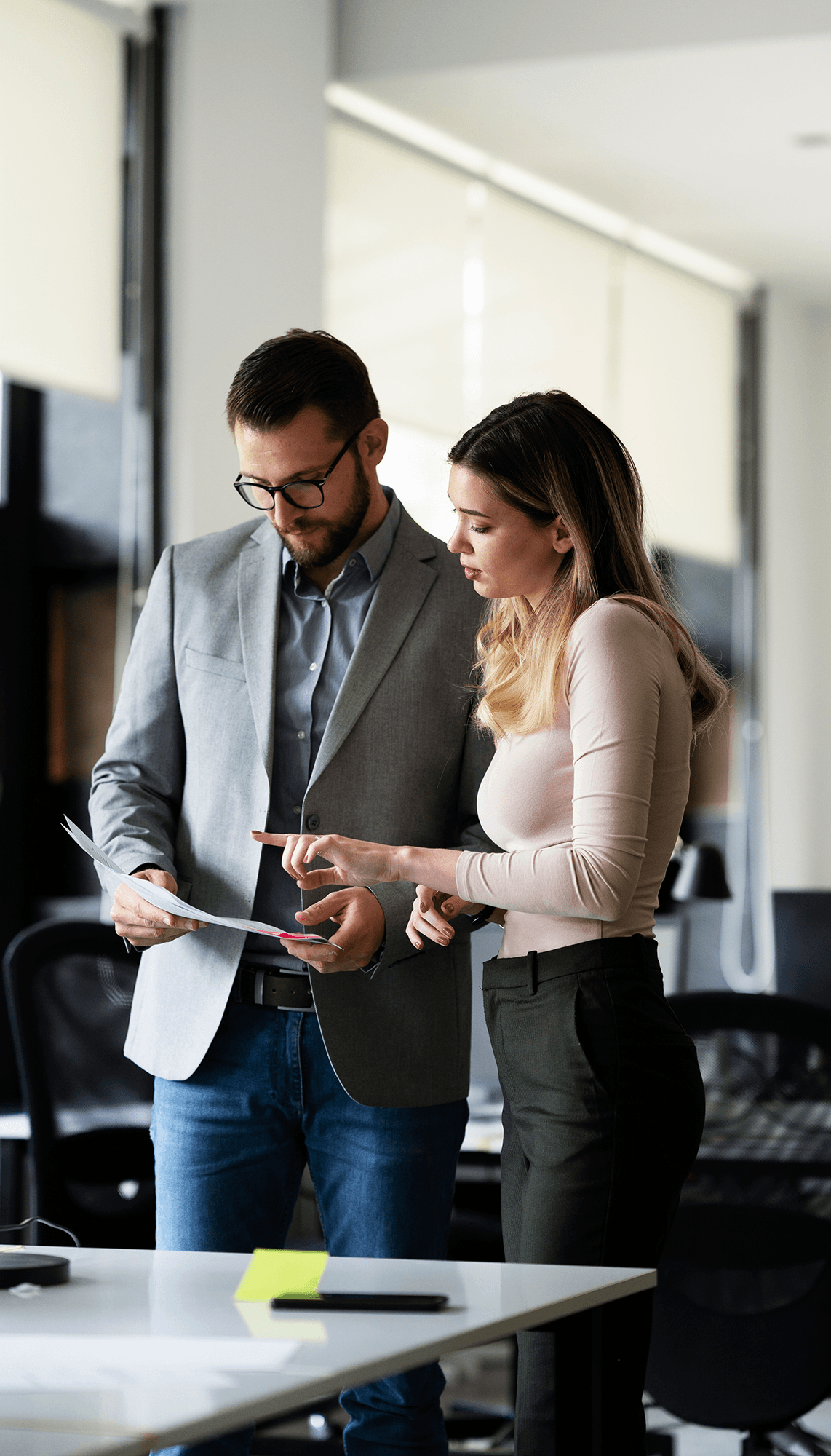 Professional man and woman reviewing documents on a tablet in a corporate office setting