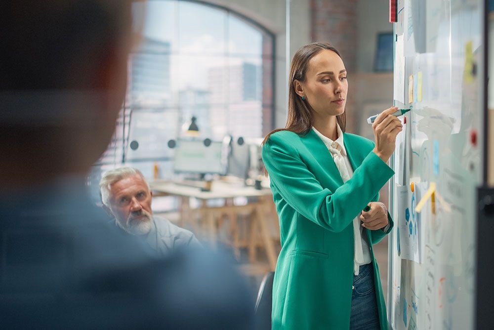 Female leader at whiteboard drawing plans