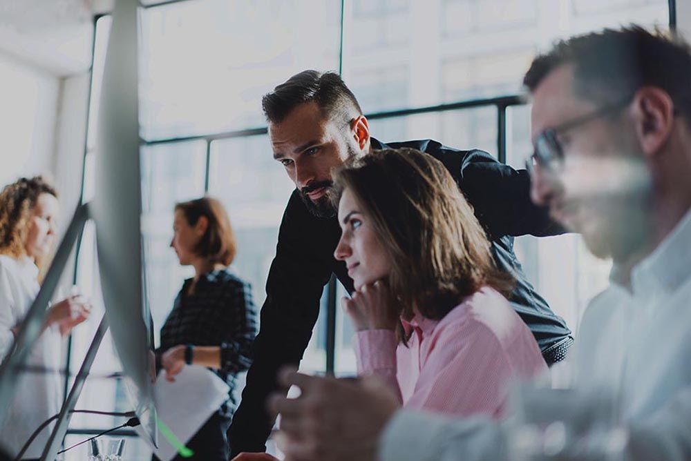 Team of professionals evaluating risks on a computer screen in a modern office environment.