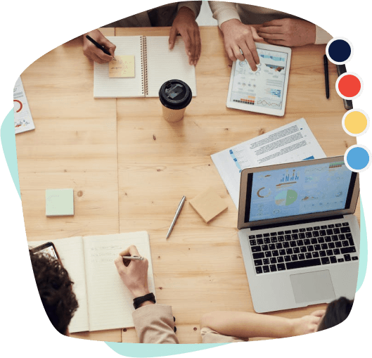 A business meeting with four people around a wooden table, taking notes..